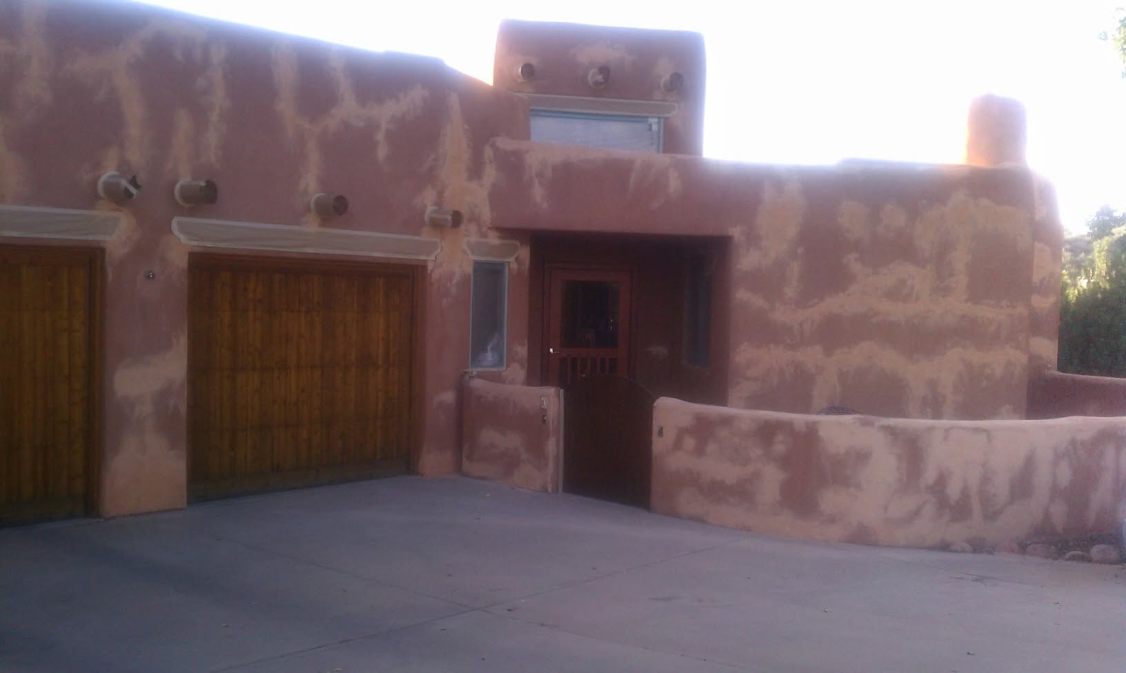 Two-story tan stucco home with deep green trim and stone accents — exterior project in Colorado Springs, CO